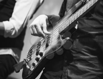 Rock music black and white background, bass guitar player, closeup photo with selective focus, selective focus