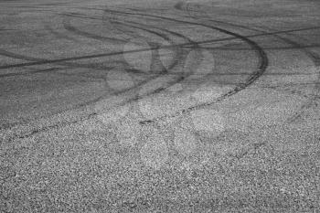 Abstract transportation background with dark tire tracks on gray asphalt road