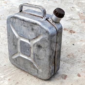 Old metallic 10l gasoline jerry can above concrete background