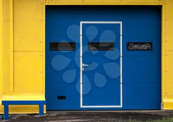 Texture of modern yellow garage wall with closed blue gate