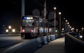 The last tram rides over a bridge on a winter night