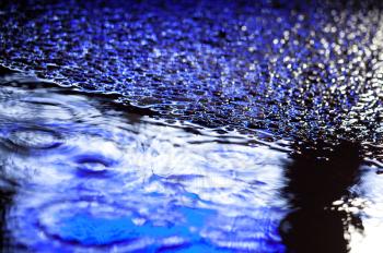 Abstract blue city rainy background with wet shining asphalt and puddle