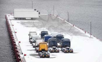 Trucks and trailers waits on snowbound pier in port