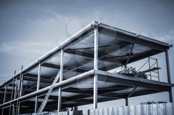 Modern industrial building is under construction. Dark blue toned photo