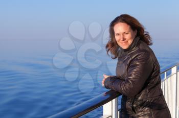 Beautiful smiling young Caucasian woman stands on the walking deck of cruise ship,  outdoor portrait
