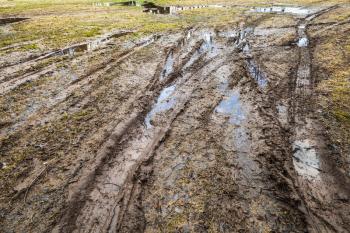 Dirty wet rural road with puddles and mud, countryside travel background