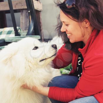 Happy young woman with white fluffy Samoyed dog, old style square photo with tonal correction filter effect