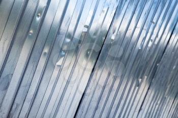 New shining corrugated metal fence, industrial wall background photo with selective focus