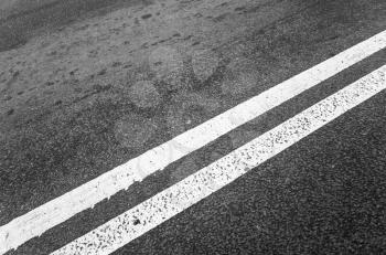 White double dividing line over black highway asphalt, closeup photo with selective focus