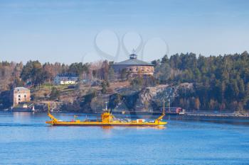 Small yellow Ro-Ro ferry goes near medieval Oscar Fredriksborgs fortification. Landmarks of Vaxholm, Stockholm archipelago, Sweden