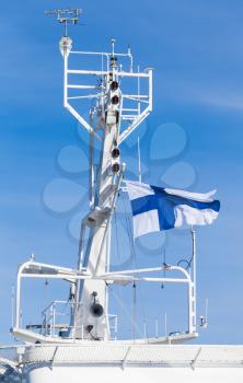 White ship mast with national flag of Finland over blue sky background
