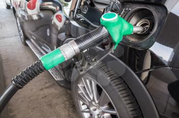 Filling a car with petrol at automatic gas station, closeup photo of fueling nozzle