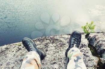 Male feet in camouflage pants and black rough shoes, travel lifestyle background. Cold tonal correction photo filter, old style effect
