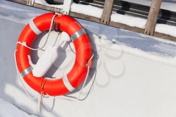 Ship safety equipment, orange lifebuoy on white boat in winter