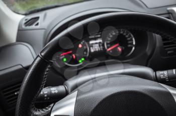 Modern car interior, steering wheel and blurred control panel, driver view point, selective focus