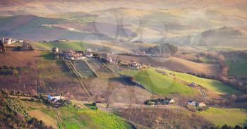 Spring rural panorama of Italian countryside. Province of Fermo, Italy. Farms and green fields on  hills