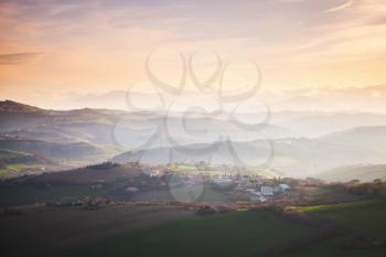 Morning panorama of Italian countryside. Province of Fermo, Italy. Villages and on hills under colorful cloudy sky