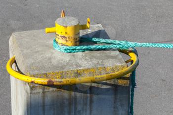 Port mooring bollard with green ship rope on it