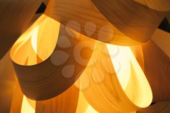 Abstract interior decoration background, lampshade made of wood veneer with bright glowing lamp inside, closeup photo with selective focus and shallow DOF