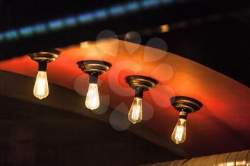Retro tungsten lamps glowing in dark interior, photo with selective focus and shallow DOF