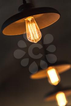 Retro tungsten lamps glowing over dark ceiling background, photo with selective focus and shallow DOF