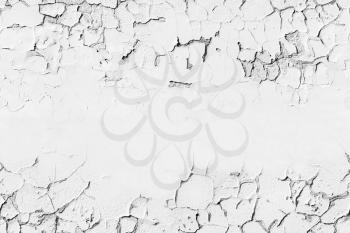 White concrete wall with cracked flaking paint layer, background texture with seamless composition and copy-space area in the center