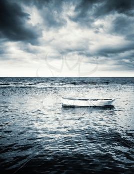 White wooden fishing boat under dramatic stormy clouds