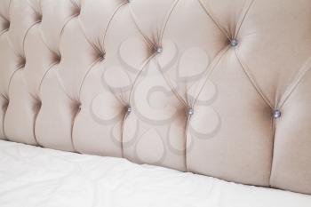 Luxury empty bedroom interior fragment, soft pink headboard and white bedding sheets on wide double bed