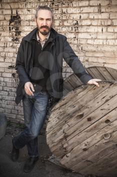Outdoor vertical portrait of young Asian man in black over gray urban grungy brick wall background