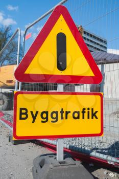 Road under construction. Exclamation warning roadsign on urban roadside. Swedish text means traffic construction