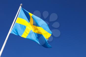 Waving on wind Swedish flag over deep blue sky background