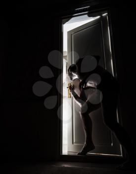 Man peeping through the door slot in black room at night