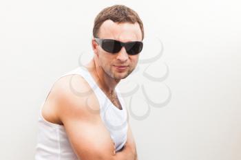 Portrait of Young sporty Caucasian man in white shirt and black sunglasses 