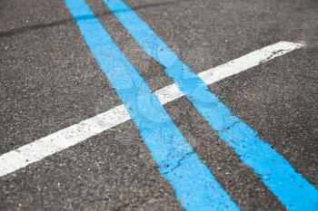 Blue double dividing line over one white on highway asphalt, closeup photo with selective focus