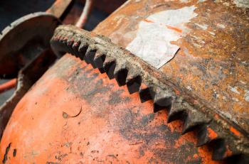 Portable concrete mixer fragment. Closeup photo of rusted barrel gearing, selective focus