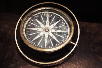 Vintage compass with old Russian coat of arms lays on dark wooden table, close up photo with selective focus and warm retro tonal correction photo filter effect