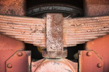 Red rusted leaf spring of industrial railway carriage, close up photo