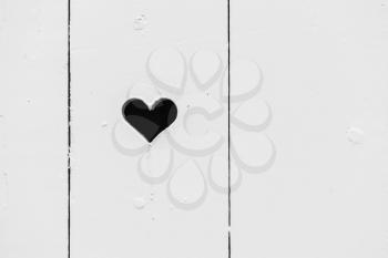 Black heart shaped hole in white wooden wall, background photo texture