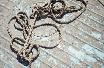 Knotted mooring rope lying on grungy boat deck