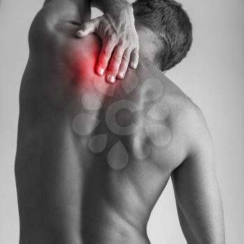 Young adult man with backache. Square black and white stylized photo with red local pain spot