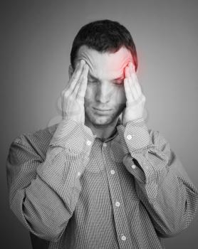 Young Caucasian man with headache. Black and white stylized photo with red local ache spot