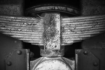 Old rusted leaf spring of industrial railway carriage, stylized black and white close up photo