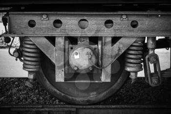 Old railway carriage wheel with suspension details, stylized black and white photo
