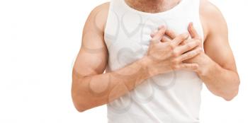 Young sporty Caucasian man in white shirt holds hands near his heart, heart pain gesture. Studio shot isolated on white