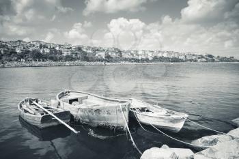 Blue toned retro stylized photo of three old wooden fishing boats moored in small port of Avcilar, Istanbul, Turkey