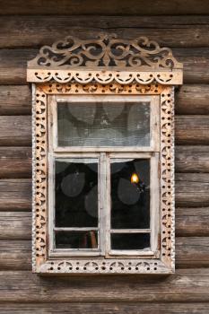 Traditional rural Russian architecture details. Window with carved wooden frame in wall made of rough logs