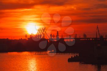 Black silhouettes of cranes and cargo ships in port of Varna at sunset