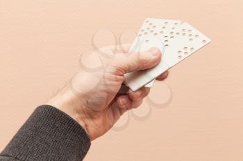 Male hand holds two plastic door key cards with holes combination code