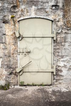Closed massive metal door in old fortification wall, background texture