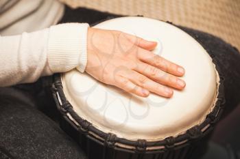 Drummer plays on African drum, closeup photo with selective focus